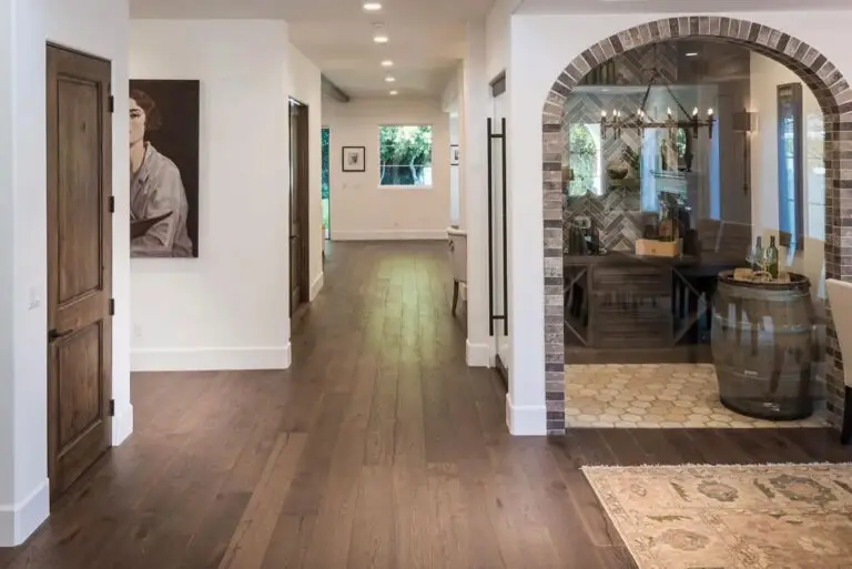 Hardwood flooring in a hallway with an arched stone doorway